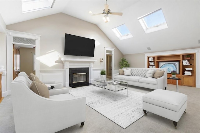 carpeted living room featuring a wainscoted wall, ceiling fan, high vaulted ceiling, and a fireplace with flush hearth