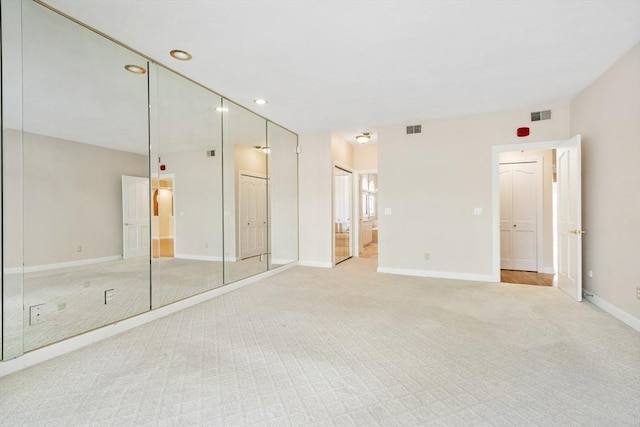 unfurnished bedroom featuring ensuite bath, baseboards, visible vents, and light colored carpet