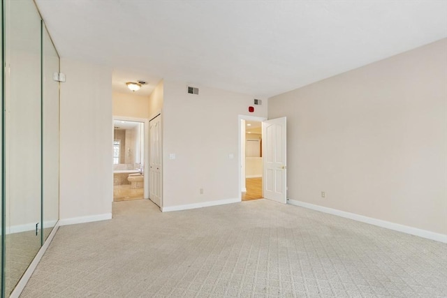 unfurnished bedroom featuring light colored carpet, visible vents, baseboards, and ensuite bathroom