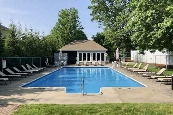 pool with a patio area, fence, and an outdoor structure