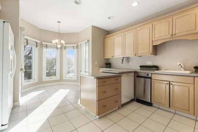 kitchen with light countertops, white appliances, light brown cabinets, and a sink