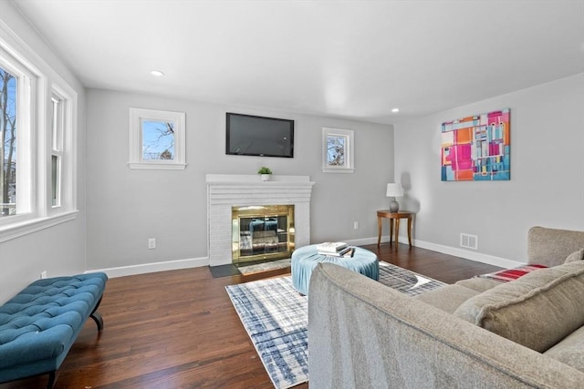 living room featuring a brick fireplace and dark hardwood / wood-style flooring