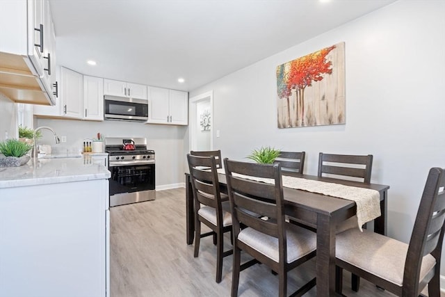 dining space with sink and light wood-type flooring