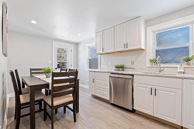 kitchen featuring sink, stainless steel dishwasher, white cabinetry, and light hardwood / wood-style floors