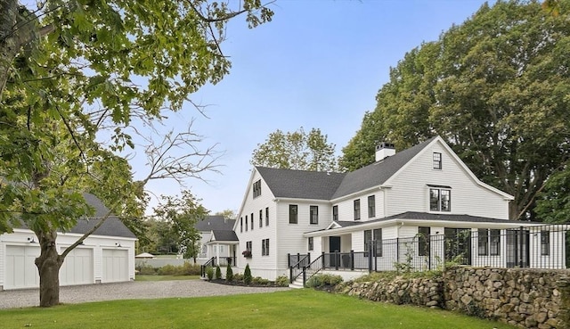 view of front of home featuring a chimney, a shingled roof, fence, and a front lawn