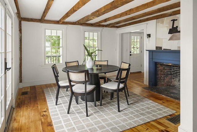 dining room featuring light wood-style flooring, beamed ceiling, and visible vents
