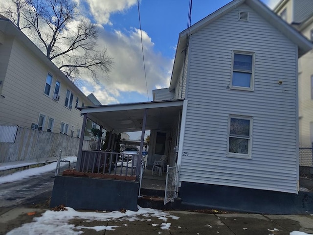 snow covered rear of property with covered porch