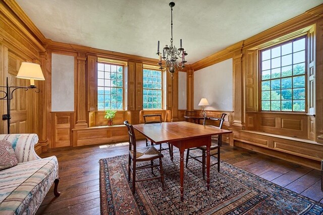 dining room featuring an inviting chandelier, wood walls, dark hardwood / wood-style flooring, and ornamental molding