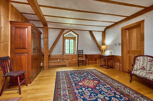 sitting room featuring light hardwood / wood-style floors, vaulted ceiling with beams, a baseboard heating unit, and wooden walls