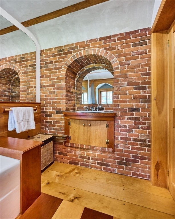 interior space with brick wall, vanity, and wood-type flooring