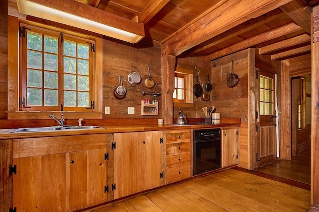 kitchen featuring wood walls, oven, beam ceiling, and light wood-type flooring