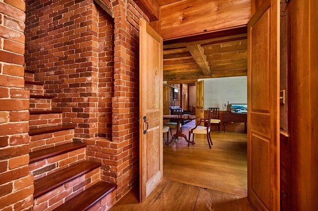 hallway featuring brick wall and wood-type flooring