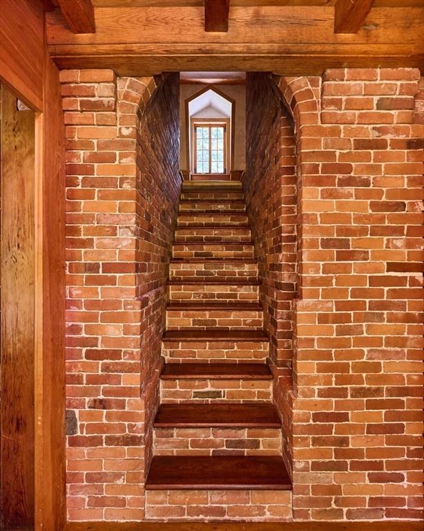 staircase with brick wall and beamed ceiling