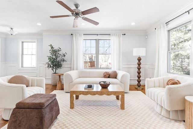 living area with a wainscoted wall, crown molding, and wood finished floors