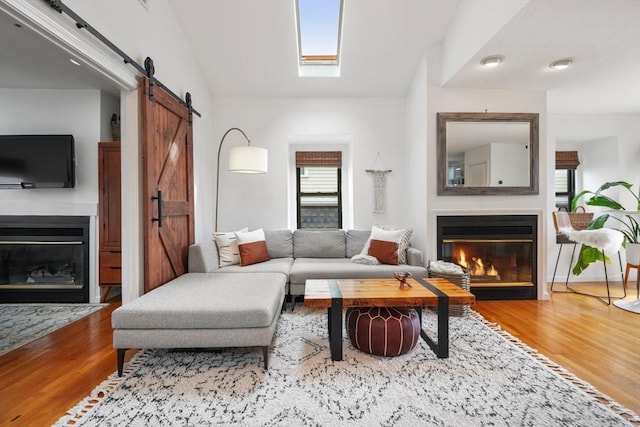 living room with hardwood / wood-style floors, vaulted ceiling, and a barn door