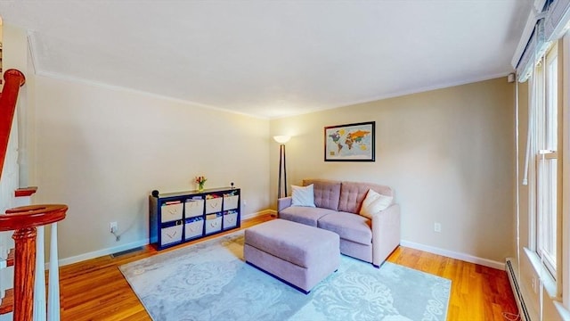 living area with baseboards, ornamental molding, light wood finished floors, and a baseboard radiator