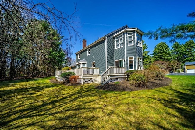 back of property with a wooden deck, a yard, and a chimney