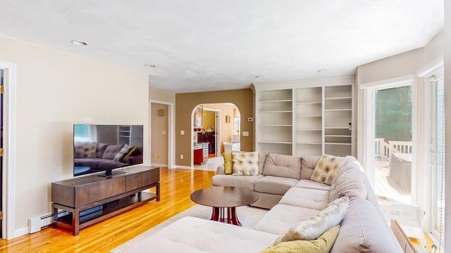 living area featuring baseboards, recessed lighting, a baseboard heating unit, arched walkways, and light wood-style flooring
