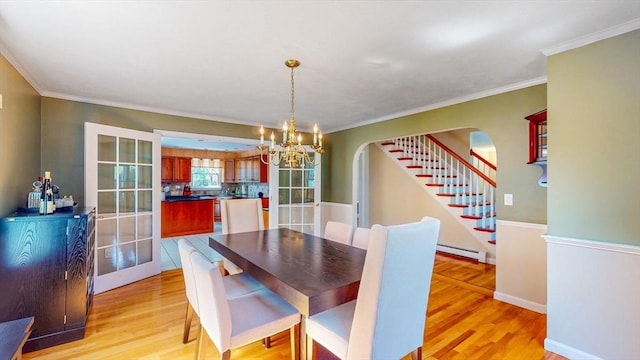 dining space with a notable chandelier, arched walkways, light wood-type flooring, a baseboard heating unit, and stairway