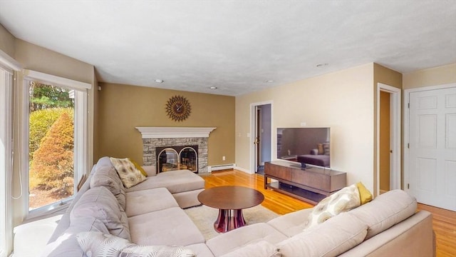 living room with recessed lighting, a fireplace, a baseboard heating unit, and light wood finished floors