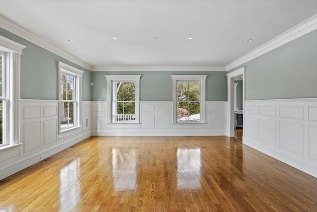 interior space with a wainscoted wall, wood finished floors, and ornamental molding