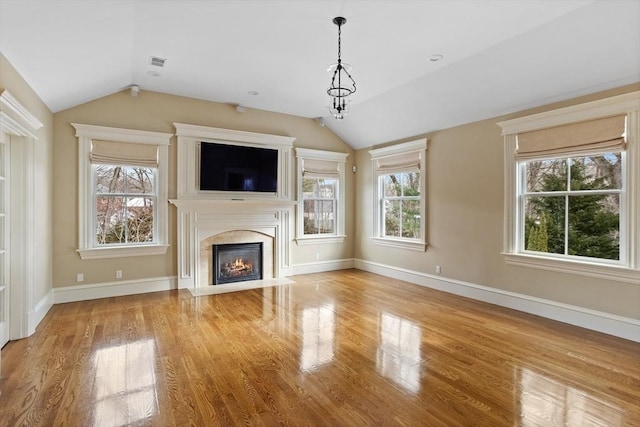 unfurnished living room featuring a fireplace, baseboards, lofted ceiling, and wood finished floors