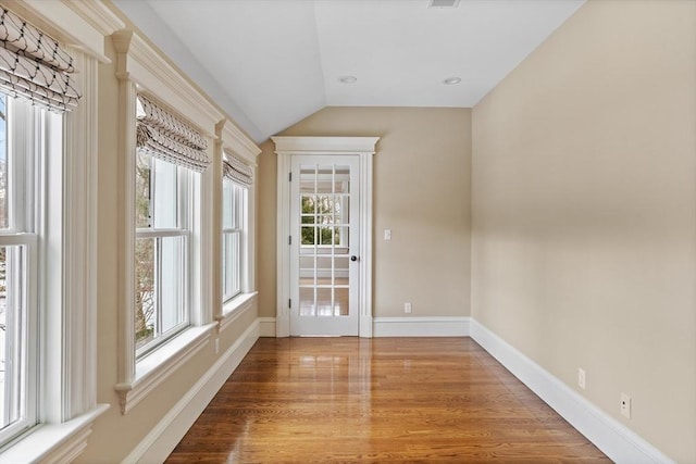 entryway with lofted ceiling, wood finished floors, baseboards, and visible vents