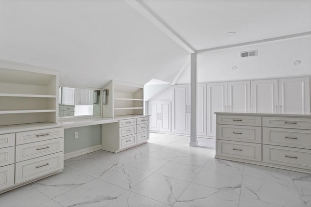 walk in closet featuring lofted ceiling with beams, visible vents, marble finish floor, and built in desk