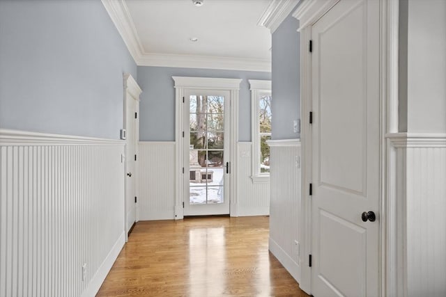 doorway featuring a wainscoted wall, light wood-style floors, and ornamental molding