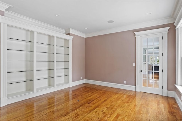 unfurnished room with crown molding, built in features, wood finished floors, and baseboards