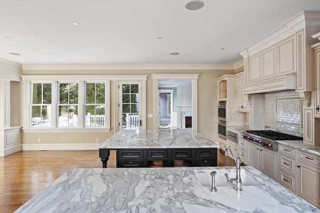 kitchen featuring a sink, stainless steel appliances, a fireplace, crown molding, and decorative backsplash