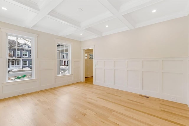 empty room featuring beam ceiling, recessed lighting, a decorative wall, light wood-type flooring, and coffered ceiling