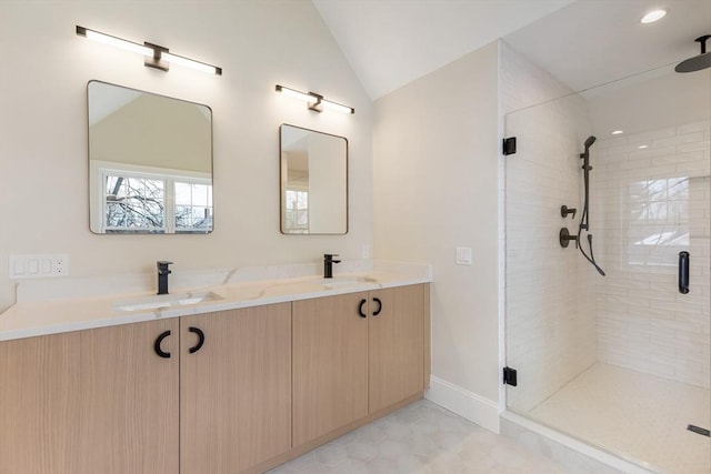 bathroom with a stall shower, vaulted ceiling, a sink, and double vanity