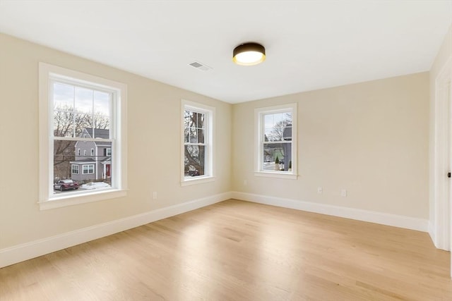 unfurnished room featuring visible vents, light wood finished floors, and baseboards