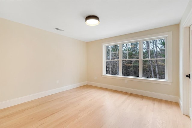 empty room featuring light wood finished floors, baseboards, and visible vents