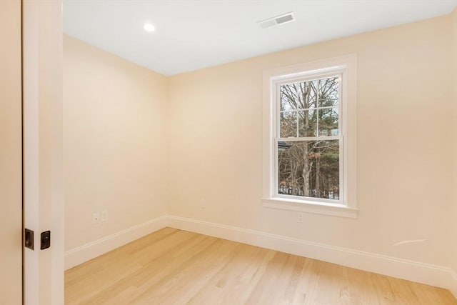 spare room featuring wood finished floors, visible vents, and baseboards