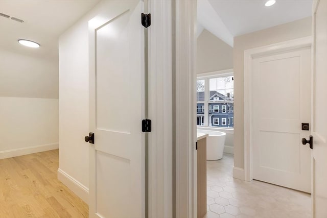 hallway featuring recessed lighting, visible vents, light wood-style floors, vaulted ceiling, and baseboards