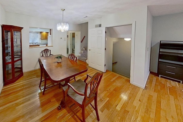 dining room with light wood-type flooring, a chandelier, stairway, and baseboards