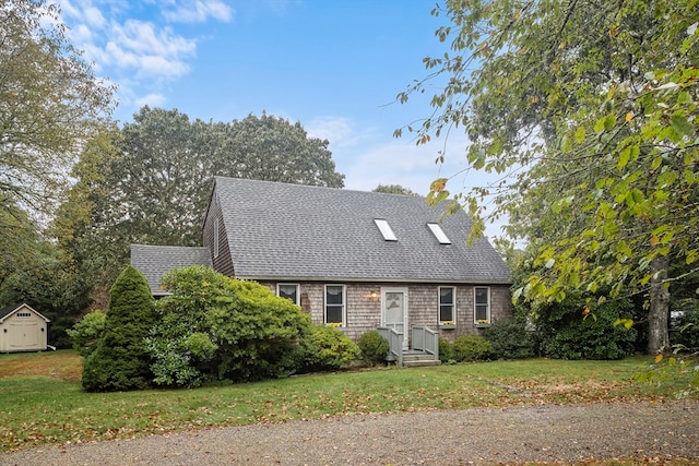 cape cod-style house with a storage shed and a front yard