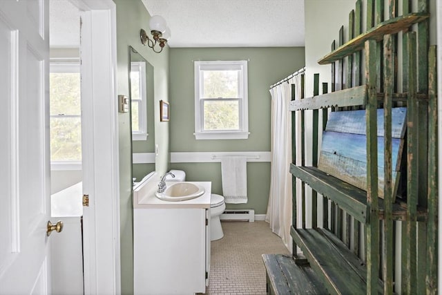 bathroom with a baseboard heating unit, toilet, vanity, and a textured ceiling