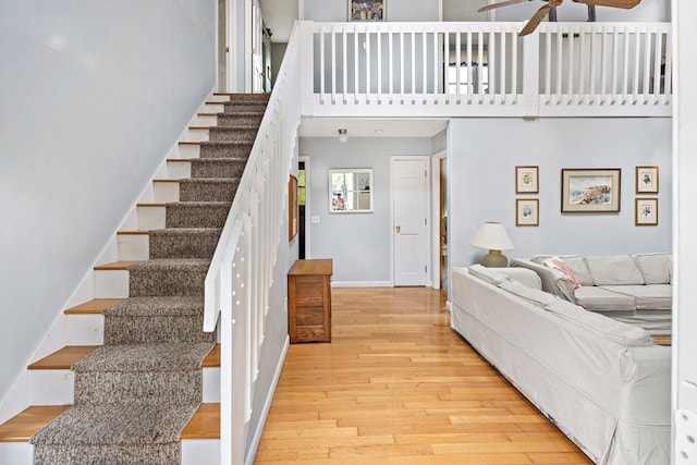 stairs with hardwood / wood-style flooring, a high ceiling, and ceiling fan