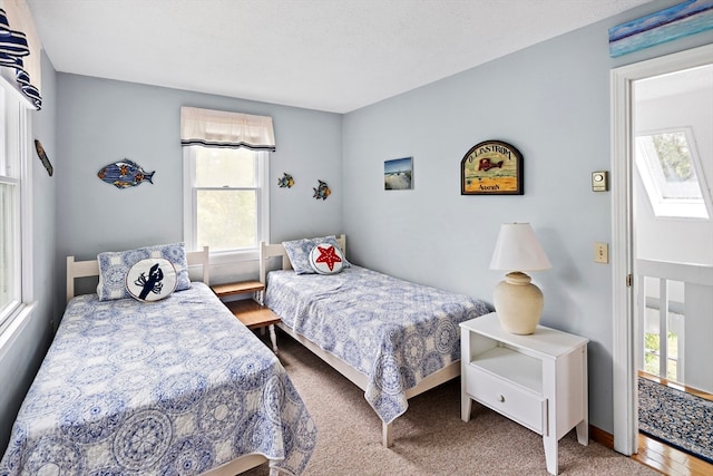 bedroom with a skylight, carpet flooring, and multiple windows