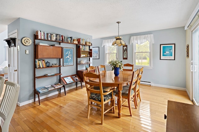 dining room with a textured ceiling, a baseboard radiator, and light wood-type flooring