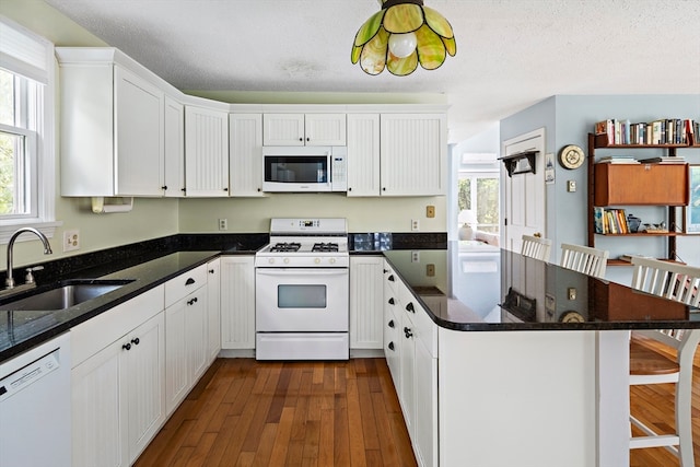 kitchen with white appliances, a textured ceiling, dark hardwood / wood-style flooring, and sink