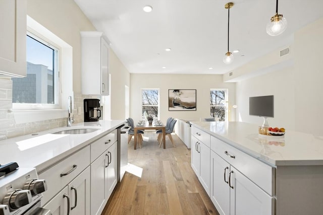 kitchen with pendant lighting, dishwasher, white cabinets, sink, and decorative backsplash