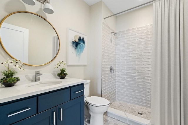 bathroom featuring a tile shower, vanity, and toilet