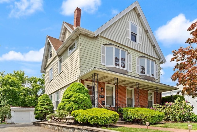 141 Jewett St Unit 2, Newton, MA 02458 - view of front of property with covered porch, a chimney, brick siding, an outdoor structure, and driveway