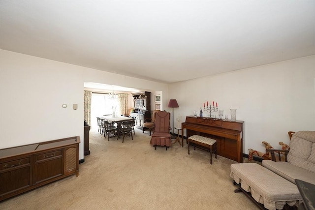 living area featuring light carpet and a notable chandelier