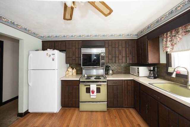 kitchen with white appliances, light wood-style floors, a sink, and light countertops