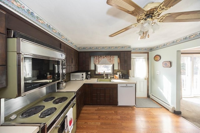 kitchen featuring plenty of natural light, white dishwasher, baseboard heating, and light countertops